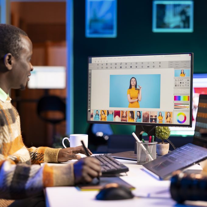 Skilled male designer using editing software on dual monitors