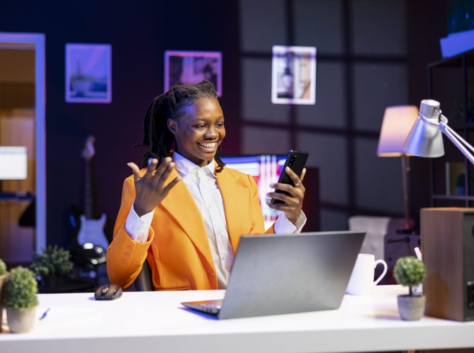 African american woman relaxing in apartment, texting friends on cellphone, enjoying leisure time. Smiling remote worker taking break to talk with mates on internet using phone